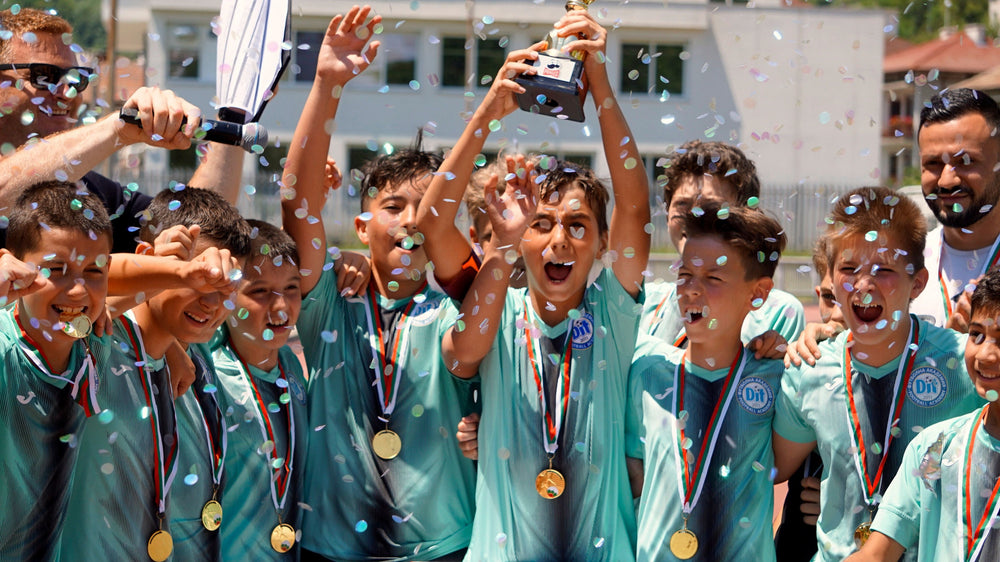 Jeunes joueurs en maillots turquoise qui fêtent une victoire, des médailles autour du cou